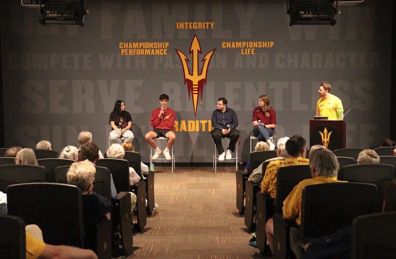 Student panel at the front of a large room addressing the audience.